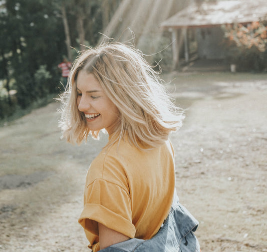 Woman spinning in yellow shirt with sun shining